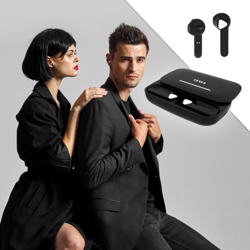 Elegantně oblečený pár, muž a žena, muž se dívá do kamery a žena šeptá muži do ucha, oba mají v uších Tesla Sound EB20 bezdrátová Bluetooth sluchátka Black Raven.